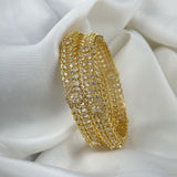 Gold bracelet with clear stones on a white fabric background