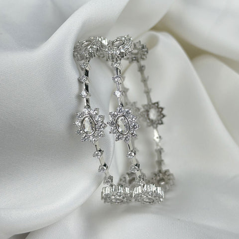 Silver earrings with intricate designs on a white fabric background