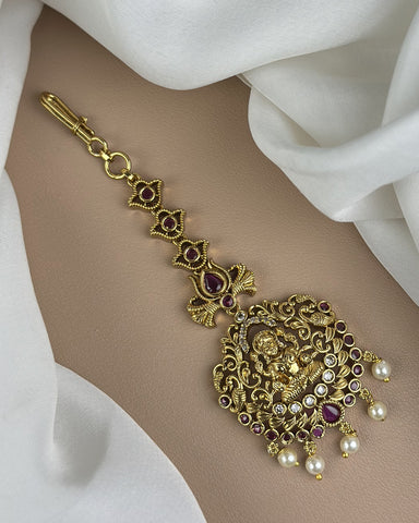 Decorative gold bracelet with gemstones and pearls on a white fabric background