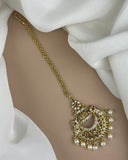 Gold anklet with intricate design on a white fabric background
