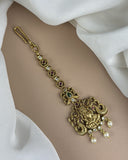 Gold bracelet with intricate design and gemstones on a white fabric background