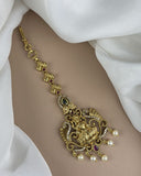 Gold bracelet with intricate design and pearls on a white fabric background