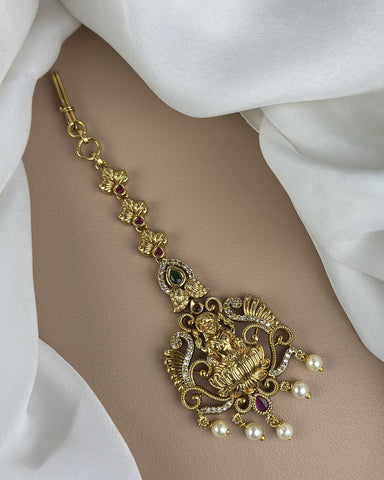 Gold bracelet with intricate design and pearls on a white fabric background