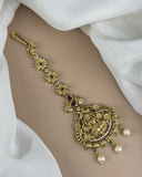 Gold bracelet with intricate design and pearls on a white fabric background