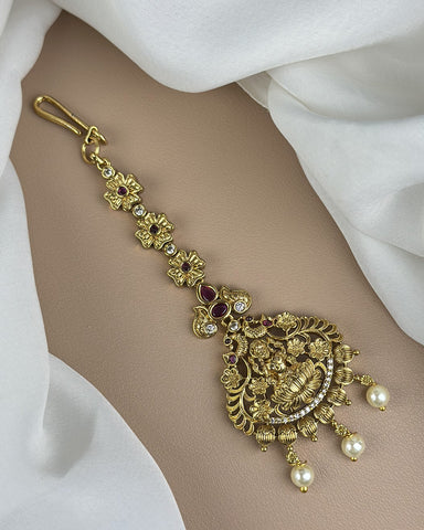 Gold bracelet with intricate design and pearls on a white fabric background