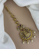 Gold bracelet with intricate design and pearls on a white fabric background