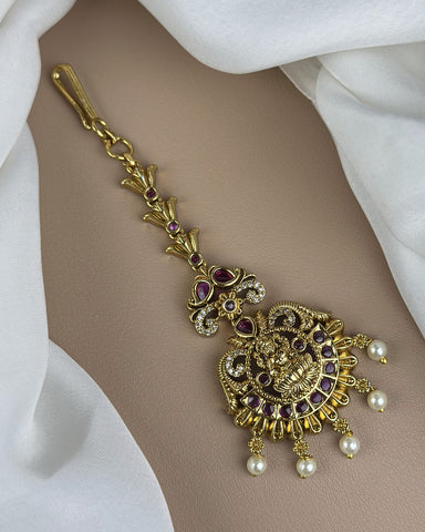 Gold bracelet with intricate design and pearls on a white fabric background