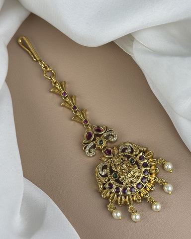 Gold decorative hairpin with pearls and gemstones on a white fabric background