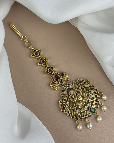 Decorative gold anklet with gemstones and pearls on a white fabric background