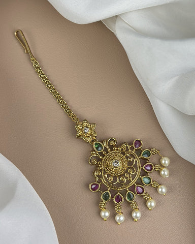Decorative gold hairpin with gemstones and pearls on a white fabric background