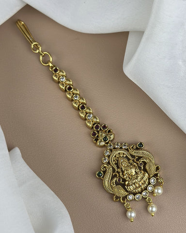 Gold necklace with intricate design and pearls on a beige background