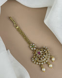 Gold necklace with intricate design and pearls on a beige background