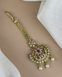 Gold bracelet with intricate design and pearls on a beige surface
