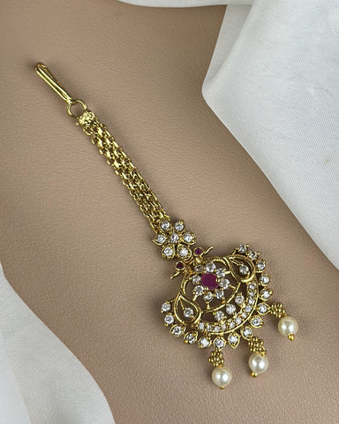 Gold bracelet with intricate design and pearls on a beige surface