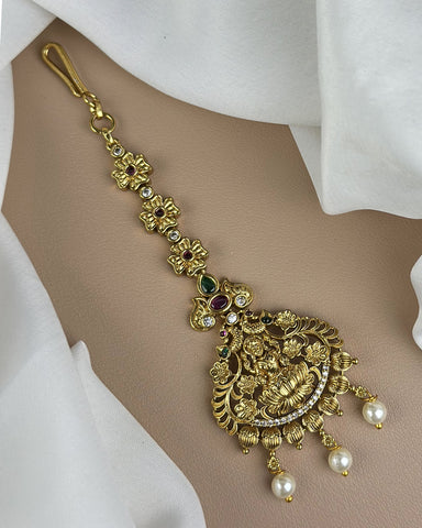 Gold anklet with floral design and pearls on a white fabric background