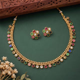 Gold-plated double-strand necklace and matching stud earrings with colorful gemstone accents, displayed on a dark green background with decorative dried flowers and a carved wooden prop.