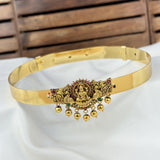 Gold belt with intricate designs and small stones on a white fabric background