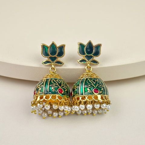 A pair of traditional Indian gold-plated jhumka earrings with green enamel, floral motifs, and dangling white pearl chains, displayed on a light beige background.