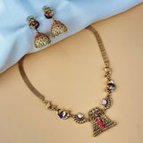 Gold necklace and earrings on a beige surface with a light blue background