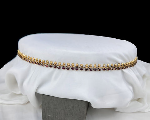 Gold bracelet with red stones on a white fabric background