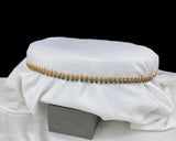 Gold and green beaded necklace on a white fabric background