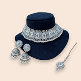 Silver jewelry set with necklace, earrings, and hairpin on a black stand against a beige background