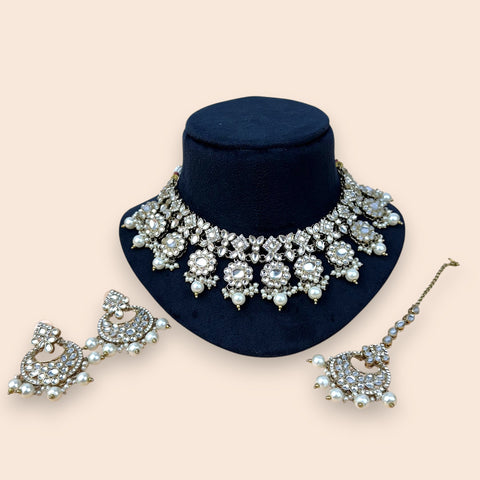 Jewelry set with necklace, earrings, and hair accessories on a beige background