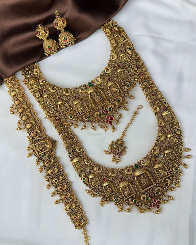Ornate gold necklace with matching earrings on a white background