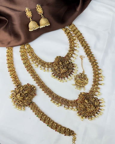 Gold necklace and earrings set on a white and brown fabric background