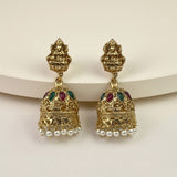 A pair of gold-toned Indian jhumka earrings with detailed filigree, small green and red stone accents, and dangling pearl beads, displayed on a clean off-white background.