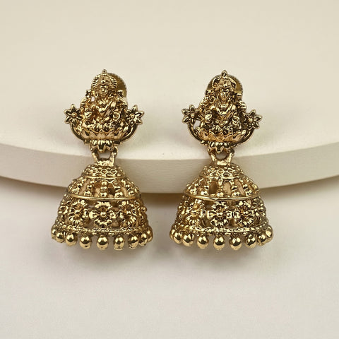 A pair of ornate gold-toned Indian jhumka earrings with detailed filigree and deity motifs, displayed on a clean white surface.