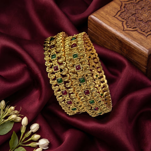 Gold bracelet with gemstones on a maroon fabric background