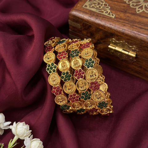 Gold bracelet with gemstones on a maroon fabric background
