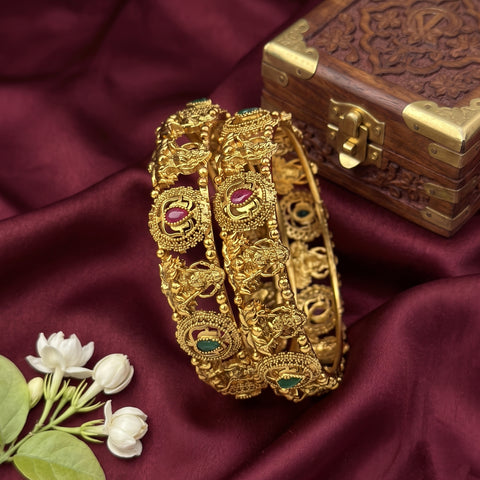 Gold bracelet with gemstones on a maroon fabric background