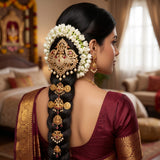 Embellished with shimmering faux diamonds, rich ruby-red stones, and delicate, dangling pearl droplets, this single jadai billa perfectly crowns the braid. It is the ultimate statement accessory for brides, festive occasions, and classical dancers looking for a blend of heritage artistry and contemporary elegance.