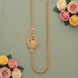A gold-toned necklace with a decorative teardrop pendant featuring a swirled motif and small clear stones, displayed on a muted green background with pink and yellow roses in the corners.