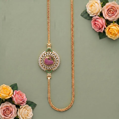 A gold-toned traditional Indian necklace with a central paisley motif, decorated with white stones and green and pink accents, displayed on a sage green background with decorative roses.
