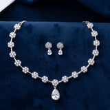 Silver-tone jewelry set featuring a necklace with floral clusters and a teardrop pendant, plus matching stud earrings, displayed on a dark blue velvet surface.
