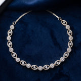 A silver-toned diamond necklace with an elegant Art Deco style, displayed on a dark blue velvet surface.