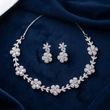 Silver floral necklace and matching drop earrings set with clear rhinestones, displayed on a dark navy velvet fabric background.