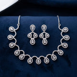 Silver-tone jewelry set featuring a necklace and matching earrings with teardrop-shaped clear stones, displayed on a dark navy velvet surface.