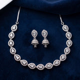 Silver-toned jewelry set featuring a teardrop-shaped necklace and matching drop earrings, both adorned with clear stones, displayed on a dark navy velvet background.