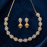 Gold-tone necklace and matching earrings set with teardrop-shaped clear stones, displayed on a dark blue velvet background.