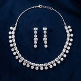 A silver-tone jewelry set featuring a collar-style necklace and matching drop earrings, both adorned with clear round and square-cut rhinestones, displayed on a dark navy blue velvet fabric background.