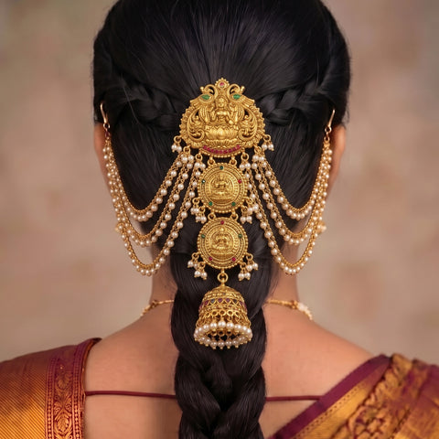 A traditional Indian gold hair ornament (jhumka) with hanging pearl strands, shown from the back on a model with styled black hair.