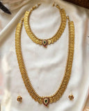 Gold-toned traditional jewelry set displayed on white satin fabric, including a long necklace, a shorter necklace, matching earrings, and ornate coin-style motifs with small green and red stone accents.