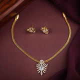 Gold-tone necklace and matching stud earrings set with clear stones, displayed on a dark burgundy fabric surface.