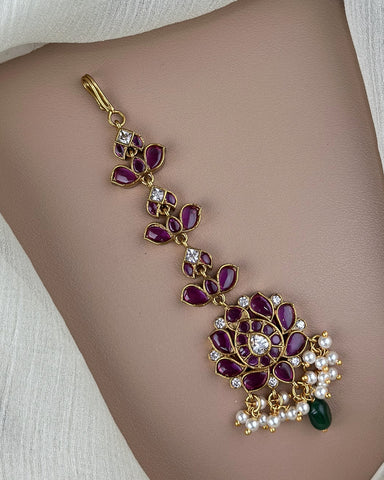 Decorative bracelet with purple stones and gold accents on a person's wrist.