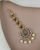 Gold necklace with red and green gemstones and pearl pendants on a beige background
