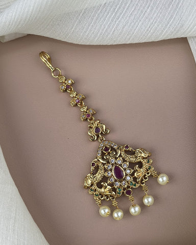 Gold necklace with pearls and gemstones on a plain background